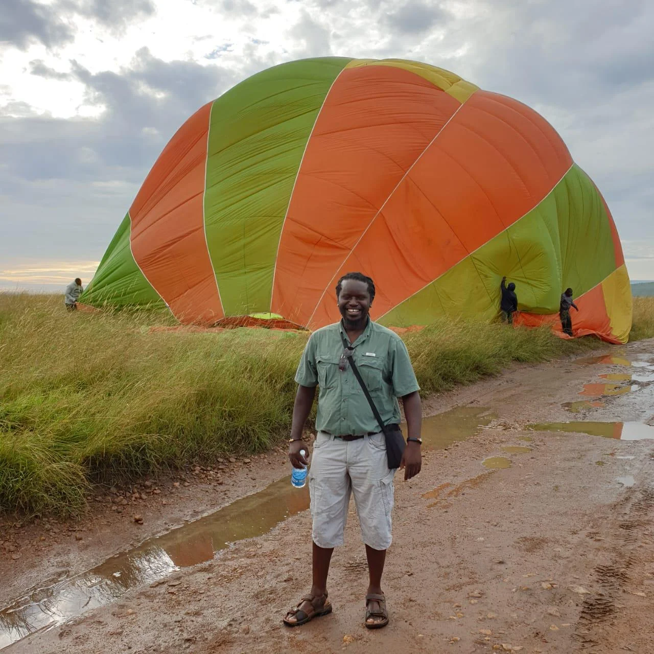 Doc on a wet track in the Maasai Mara beside a hot air balloon being packed down after a dawn flight