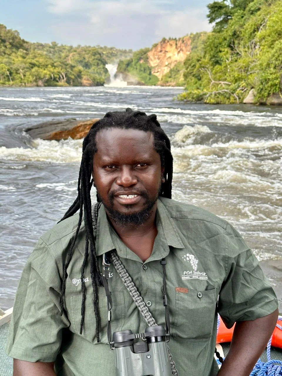 Doc on a boat below Murchison Falls in Uganda, binoculars around his neck