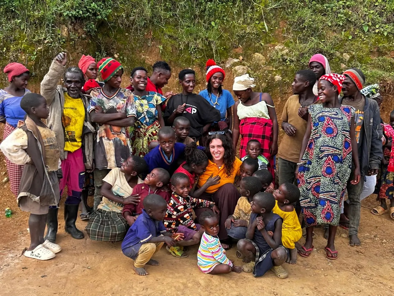 A POA group sitting among Batwa villagers and children during a community visit