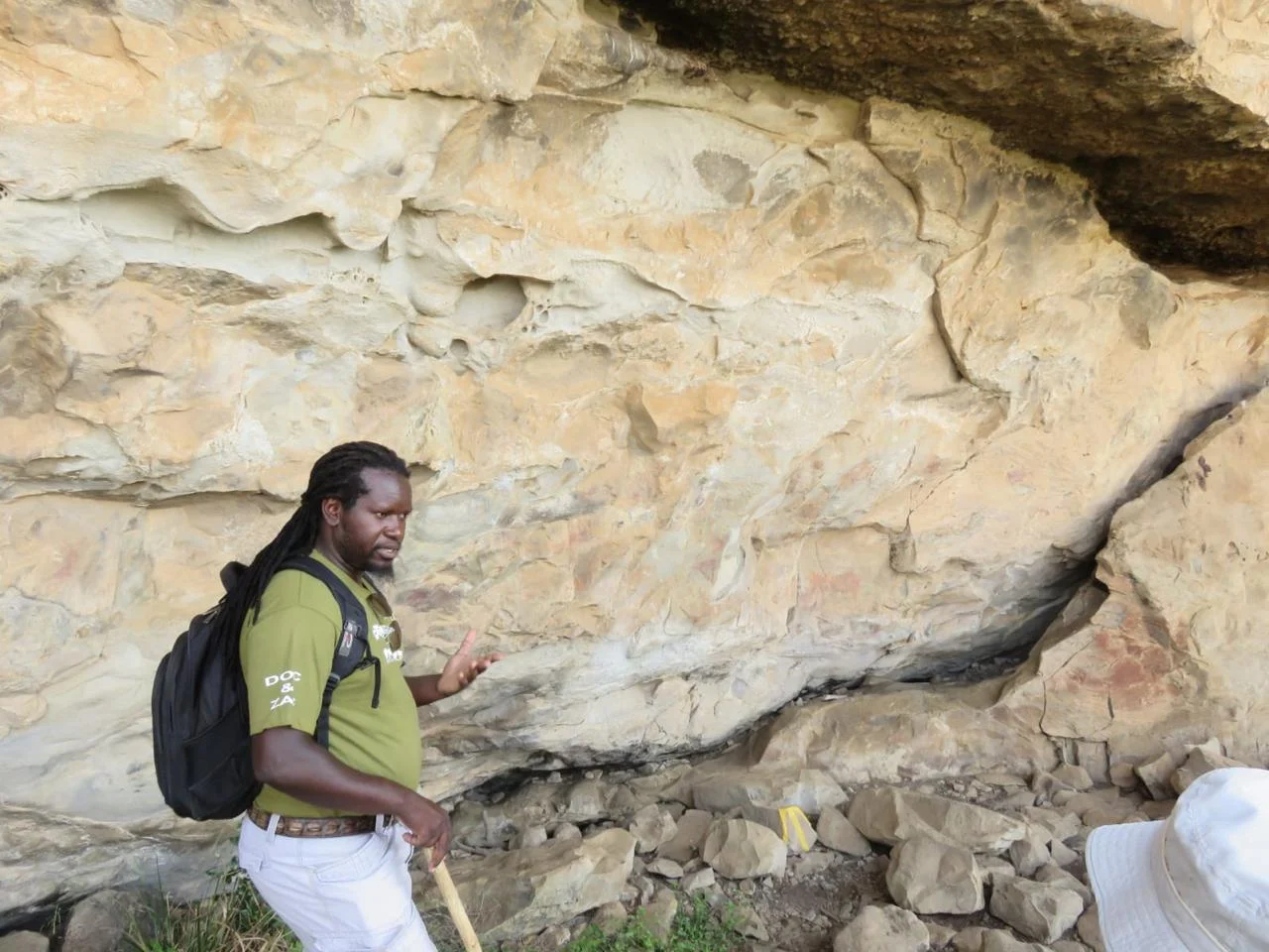 Doc pointing out San rock paintings on a sandstone overhang in the Drakensberg, a guest beside him
